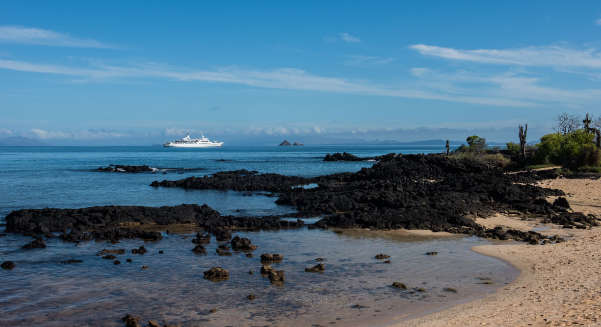 Dragon Hill - Santa Cruz in the Galapagos Islands, view of volcanic beach and the Galapagos Legend in the sea